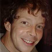 Smiling man with curly, reddish-brown hair